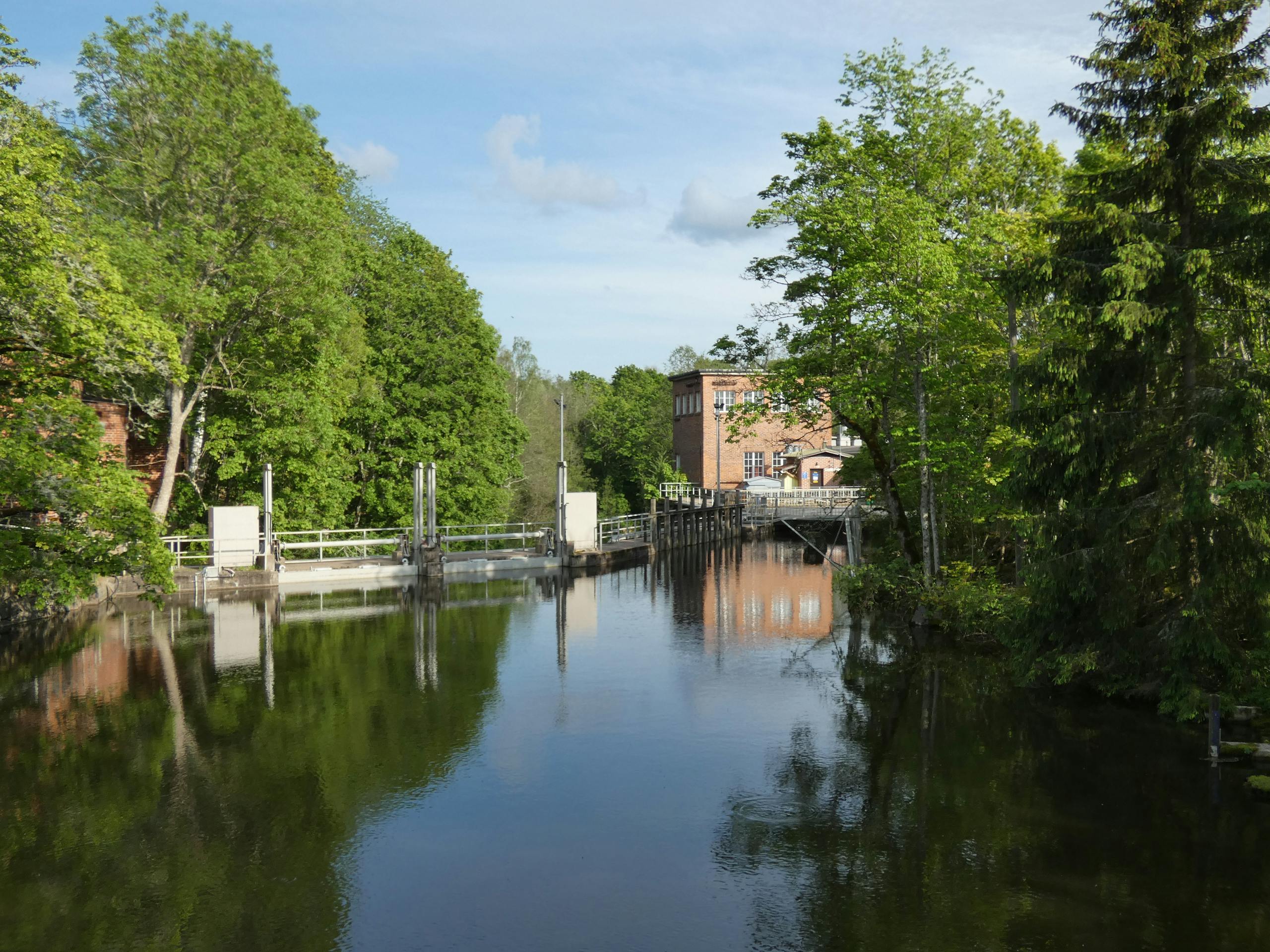 Serene river with a dam and lush greenery under a clear sky, perfect for nature photography.